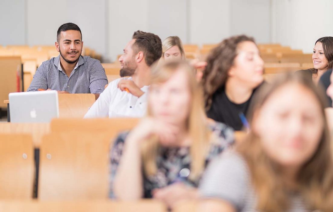 Studierende unterhalten sich in einem Hörsaal